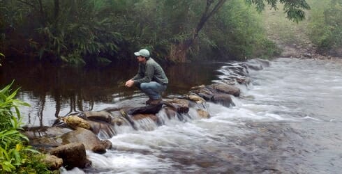 photo: man near stream - Water funds help to provide fresh water today and into the future.