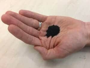 photo: hand holding black, engineered sand.