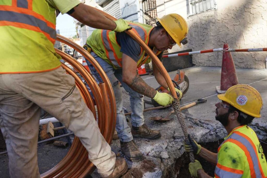 Utility workers replacing a residential water service line with new copper pipes.